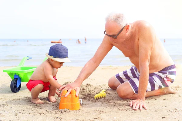 Ragazzino e nonno che giocano in spiaggia — Foto Stock