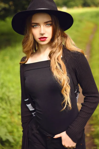 Giovane bella ragazza con lunghi capelli ricci e labbra rosse in cappello nero — Foto Stock