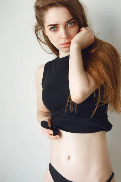 Krásná bruneta s dlouhými vlasy v černé tričko a spodní prádlo pózuje na černém pozadí — Stock fotografie