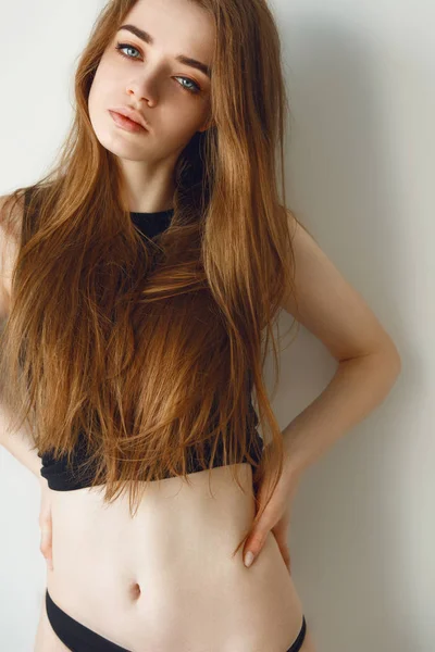 Bella bruna con i capelli lunghi in t-shirt nera e biancheria intima in posa su sfondo nero — Foto Stock
