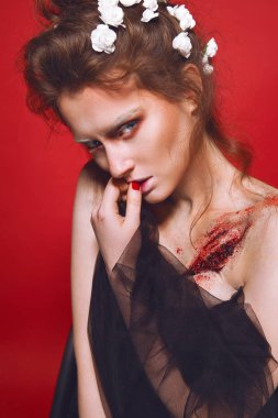 Kumral saç beyaz çiçeklerle ve kanlı yaralar kırmızı zemin üzerine göğsüne ile