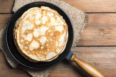 Ahşap bir masa üzerinde bir dökme demir tava üzerinde krep yığını
