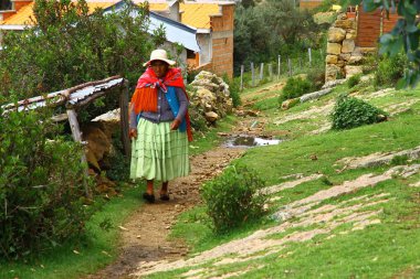 Isla del Sol, Titicaca Gölü, Bolivya, Toprak yolda yürüyen hasır şapkalı yaşlı kadın