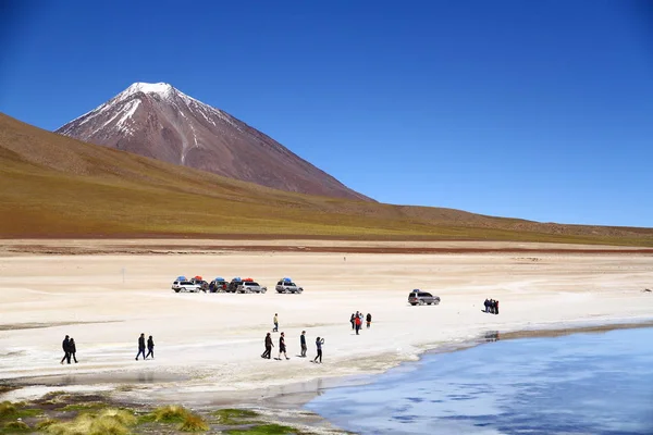 人々は湖のそばを歩いていて ライセンスバー火山はボリビアの背景にあります — ストック写真