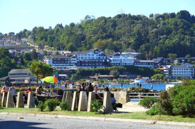 A view from the Puerto Varas streets. People are spending time by the lakeside on a sunny day clipart
