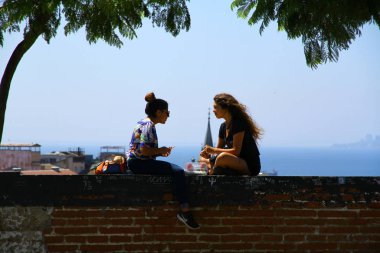 Şili 'deki Valparaiso Kültür Parkı' nda genç kadınlar duvarda sohbet ediyorlar.