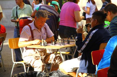 İnsanlar Şili 'nin ana meydanı olan Plaza de Armas' ta bir turnuvada satranç oynuyor.