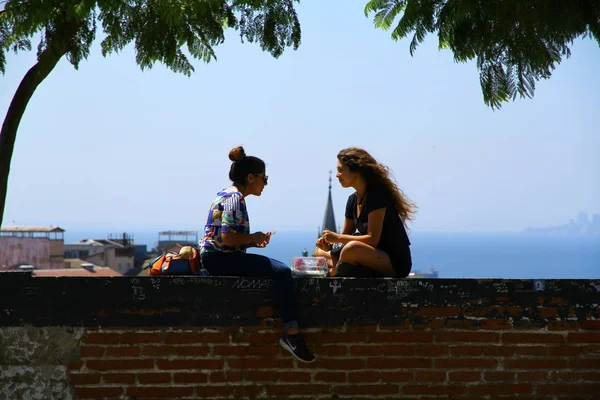Şili 'deki Valparaiso Kültür Parkı' nda genç kadınlar duvarda sohbet ediyorlar.