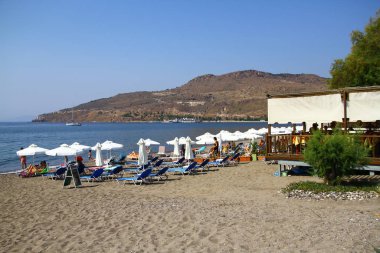 Kumsalda şemsiyeli ve güneşli yataklı.