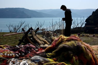 SARIYER, ISTANBUL, TURKEY - 13 March 2011. A fisherman is repairing his net in Garipce village.
