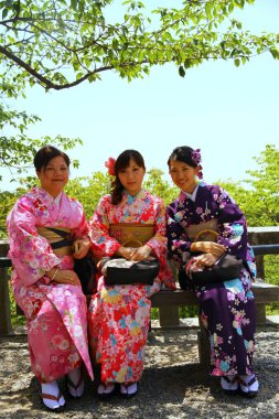Kyoto, Japonya - 26 Mayıs 2013. Geleneksel kimonolu genç kadınlar Kiyomizu-dera tapınağının bahçesinde dinleniyorlar..