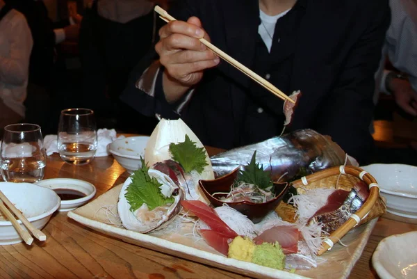 日本人男性がお箸で刺身を食べています ストックフォト