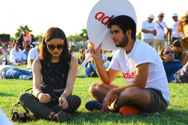 Festivalde çimlerin üzerinde oturan gençlerin görüntüsü