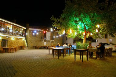 Akşamları sokakta renkli lambalar olan küçük, rahat restoranın manzarasına bak. 
