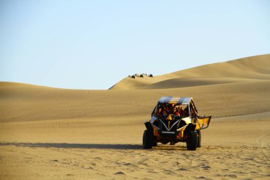 HUACACHINA, PERU - 11 April 2019. car with people who do sand boarding on the sand dunes of Huacachina. clipart