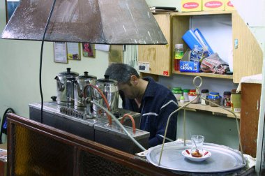 View on the bartender at the bar with the jug with tea, glass, and sugar bowls on a tray, Turkish style