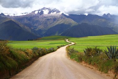 Çarpık bir yolu, yeşil çayırları ve karlı dağları olan muhteşem bir manzara, Kutsal Vadi, Peru.