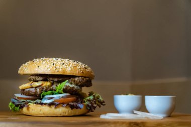 Et, yumurta, salata, soğan halkaları ve ahşap tepside soslu büyük taze bir hamburger.