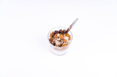 Beyaz arka planda chia pudingi, yoğurt, reçel, meyve, kurabiye ve bademlerden oluşan vejetaryen bir çöl.