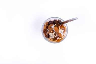 Beyaz arka planda chia pudingi, yoğurt, reçel, meyve, kurabiye ve bademlerden oluşan vejetaryen bir çöl.