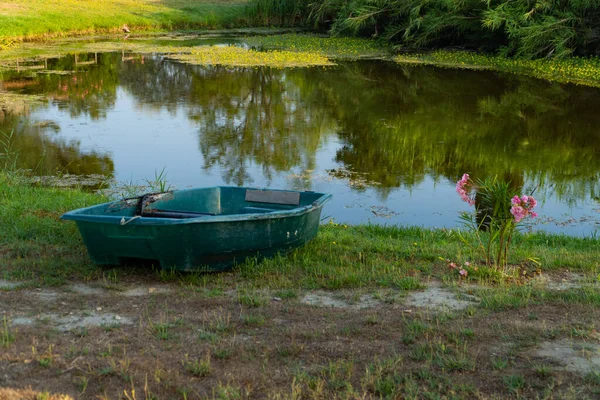 Ein kleiner See mit einem grünen Ruderboot, das im Gras liegt — Stockfoto