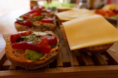 Tahta tepside avokado, domates ve vejetaryen peynirli vejetaryen sandviçler.