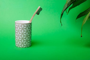 Yeşil arka planda yaprakları olan bir bambu diş fırçası.