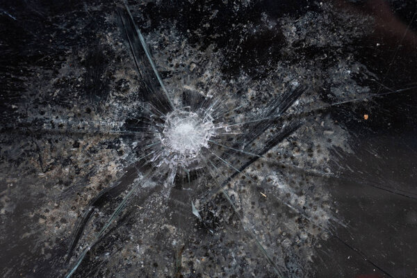 Cracks in a window glass coming from a bullet