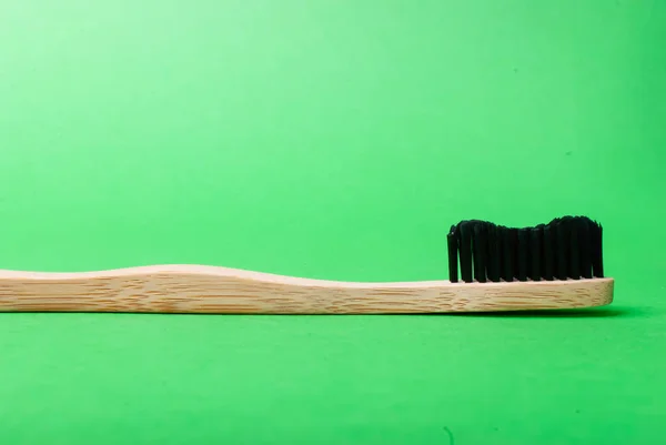 Side view of a bamboo toothbrush on green background — Stock Photo, Image