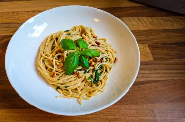 Kendinde yapılan vegan spagettisi beyaz bir tabakta, ahşap bir masanın üzerinde duruyor.