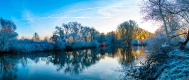 Renkli gündoğumu sırasında kış sabahının erken saatlerinde bir nehrin manzarası