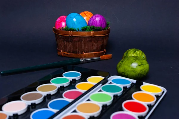 Decorating colorful easter eggs with a paintbrush on black background — Stock Photo, Image