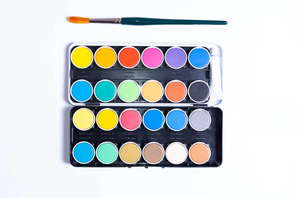 Et farverigt malersæt og en pensel på hvid baggrund - Stock-foto