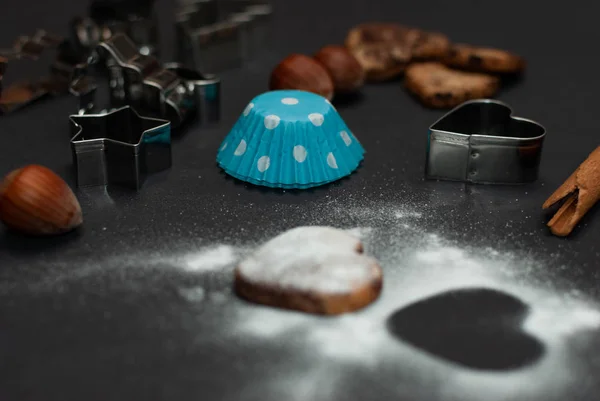 Angled view of cookies and baking equipment on black background — Stock Photo, Image