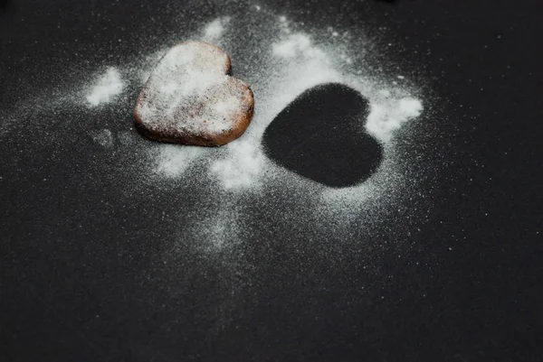 Angled view of a cookie with sugar powder on black background — Stock Photo, Image