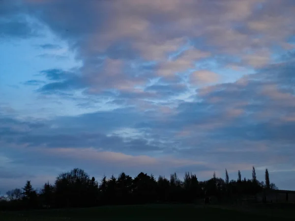 Een groen veld bij zonsondergang met daarboven een prachtige wolkenformatie — Stockfoto