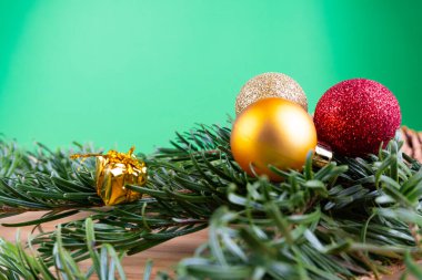 Yeşil köknar dalları ve noel süsleri (noel mücevherleri, şeker kamışı, hediyeler) yeşil bir arkaplanda, fotokopi alanı olan ahşap bir masanın üzerinde.