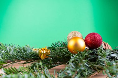 Yeşil köknar dalları ve noel süsleri (noel mücevherleri, şeker kamışı, hediyeler) yeşil bir arkaplanda, fotokopi alanı olan ahşap bir masanın üzerinde.