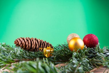 Yeşil köknar dalları ve noel süsleri (noel takıları, şeker kamışları, hediyeler, köknar konisi) yeşil bir arkaplanda, fotokopi alanı olan ahşap bir masa üzerinde