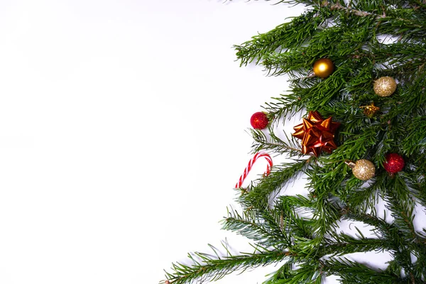 Ramas de abeto verde con adornos navideños (adornos navideños, bastones de caramelo, regalos) sobre fondo blanco — Foto de Stock