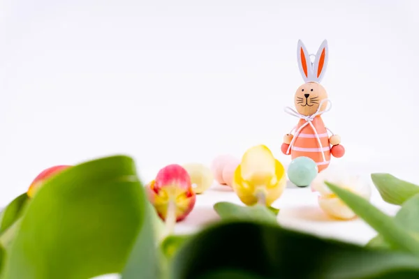 Colorful tulips laying in a row with easter eggs and a easter bunny on white background with copy space