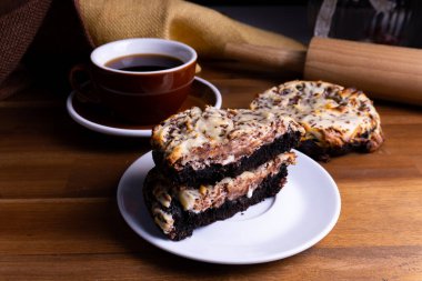 Çikolatalı kurabiyeler ve bir fincan kahveli cheesecake. Tahta üzerinde fotokopi alanı olan bir fincan kahve.