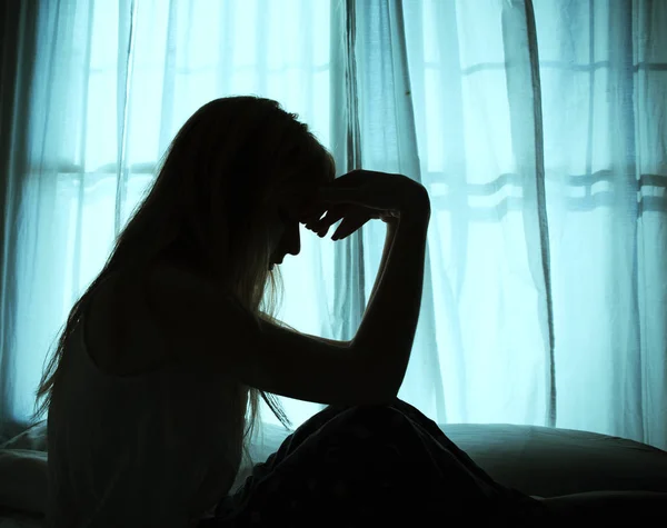 Silhouette of woman sitting in bed by window — Stock Photo, Image