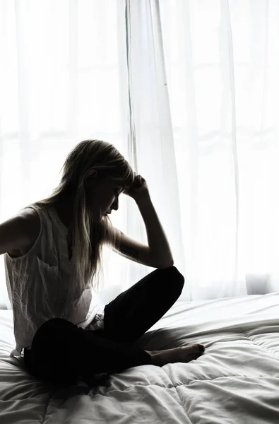 Silhouet van de vrouw zitten in bed van venster — Stockfoto