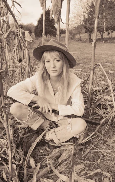 Mulher bonita sentada no campo de milho com uma arma — Fotografia de Stock