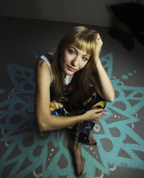 Young blond woman sitting on a painted floor — Stock Photo, Image