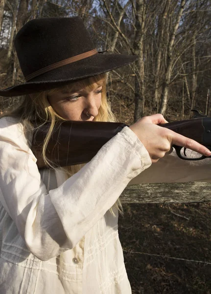 Jeune femme blonde tenant un pistolet dans les bois — Photo