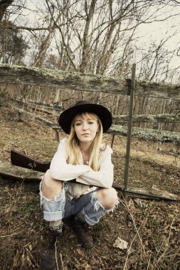 Silahla ormanda şapka siting giyen genç sarışın kadın 