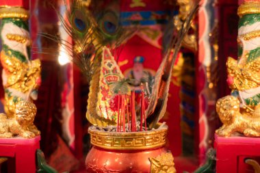Red incense stick in a golden incense burner.