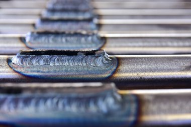 Kaynak makinesi boruya kaynak yapıyor. Tungsten Inert Gas Kaynak İşlemi (TIG). Kaynakçı koruyucu bir maske ve ısıya dayanıklı eldivenler takıyor.